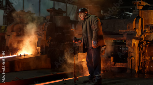 Heavy Industry Worker Doing Quality Control in Foundry. Rough Industrial Environment. Wide Shot.