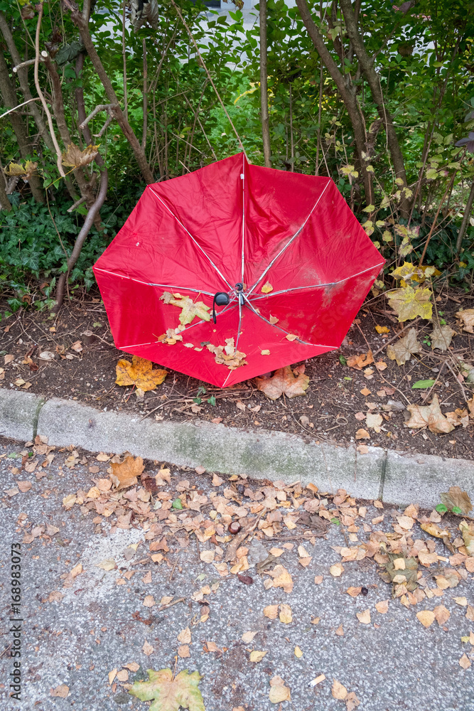 Broken red umbrella on the side of the road