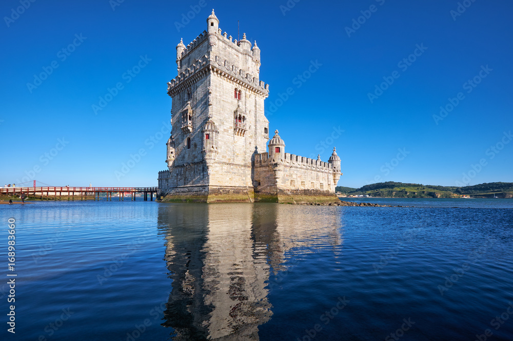 Belem Tower on river Tagus in Lisbon with reflection in water on blue sky background, Portugal