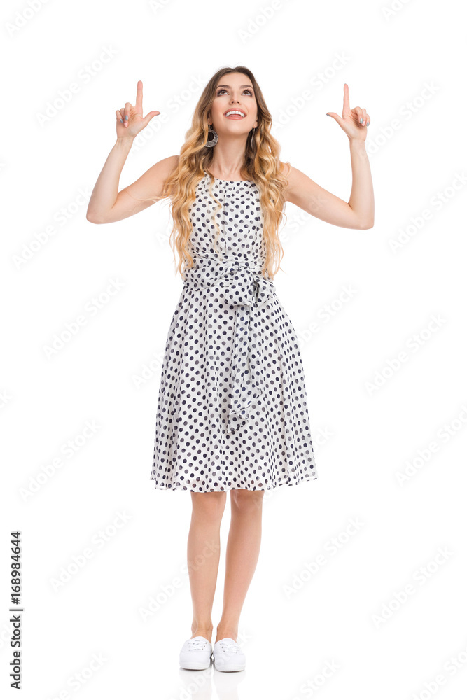 Curious Young Woman In White Dotted Dress Is Looking Up And Pointing Curious Young Woman In White Dotted Dress Is Looking Up And Pointing