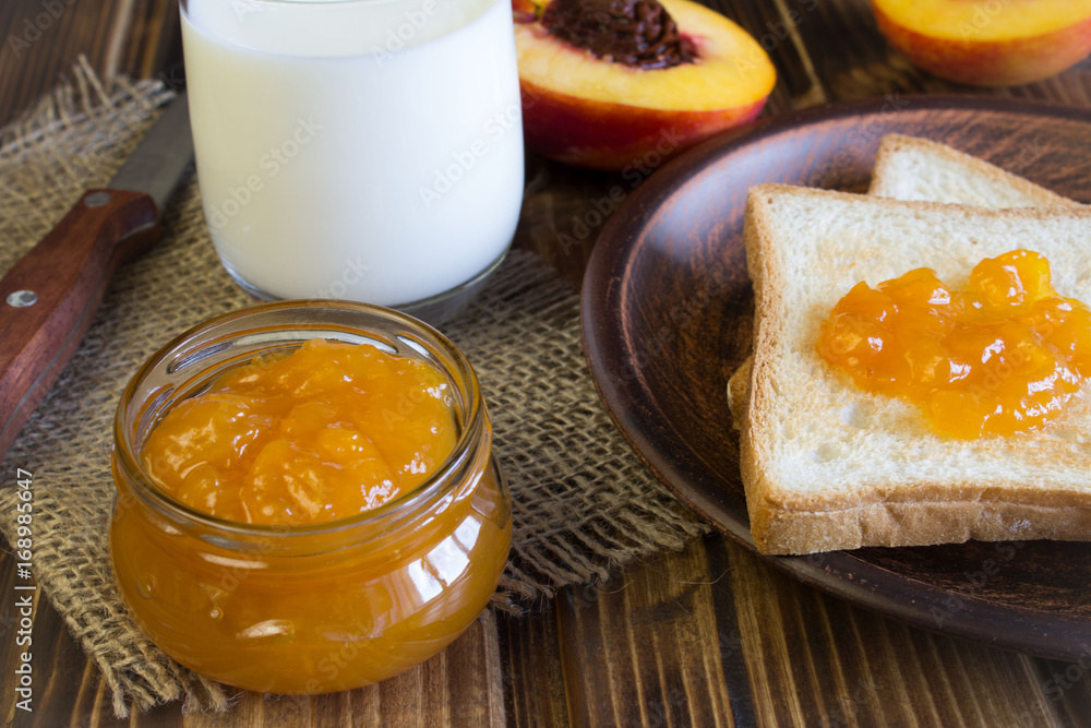 Breakfast with bread toasts, nectarine jam and milk on the brown wooden background Breakfast with bread toasts, nectarine jam and milk on the brown wooden background
