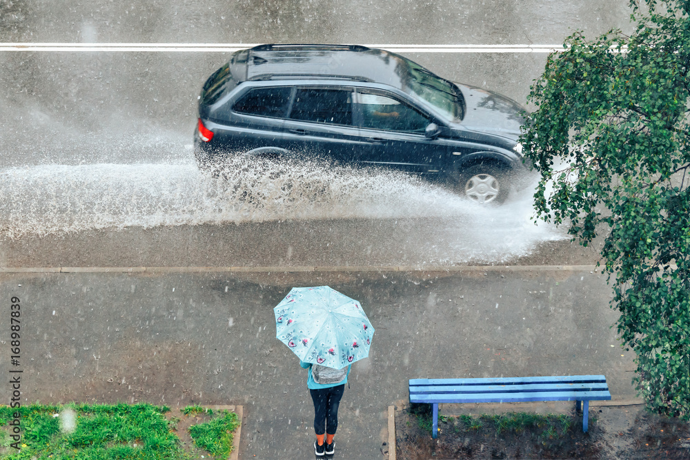 girl with umbrella standing under the rain at the bus stop