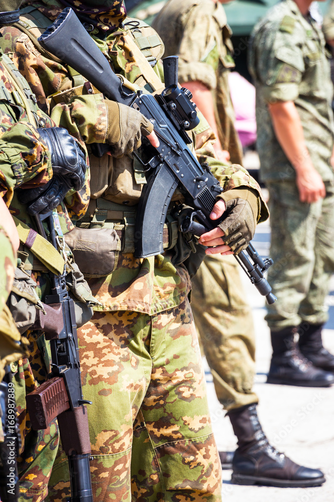 Fototapeta premium Soft focus. Soldier in camouflage holding a finger on the trigger of a Kalashnikov