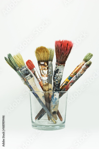 Old paint brushes in a glass, isolated on white