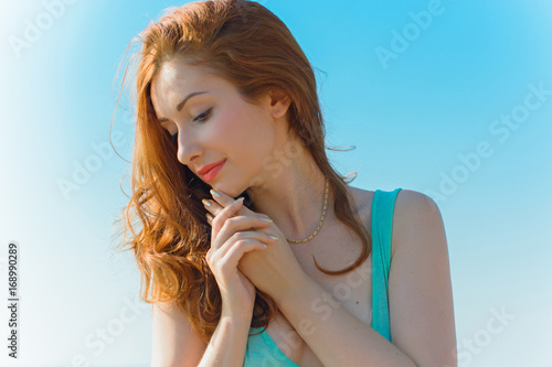 Young sexy thin and hot red hair woman on vacation in a island in blue dress and near blue water and beach pleasure and relax at warm harmony day