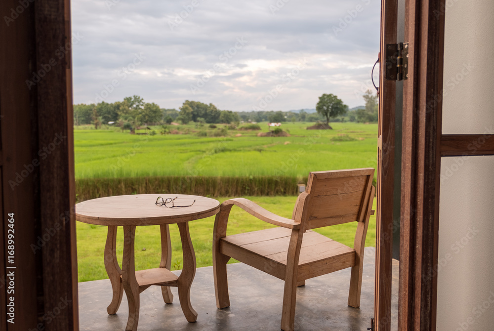 Glass on table with rice field background.