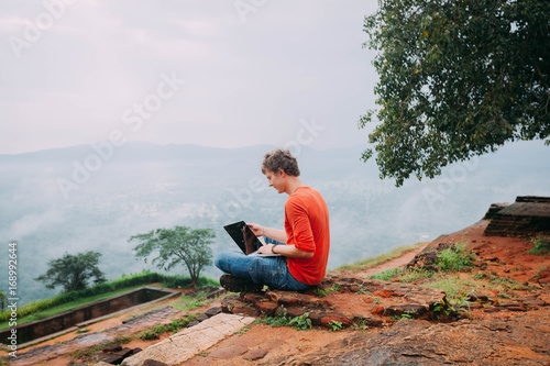 A man with laptop work outdoor on nature. Sri Lanka