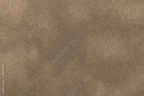 Background of light bronze suede fabric closeup. Velvet matt texture of sand nubuck textile.