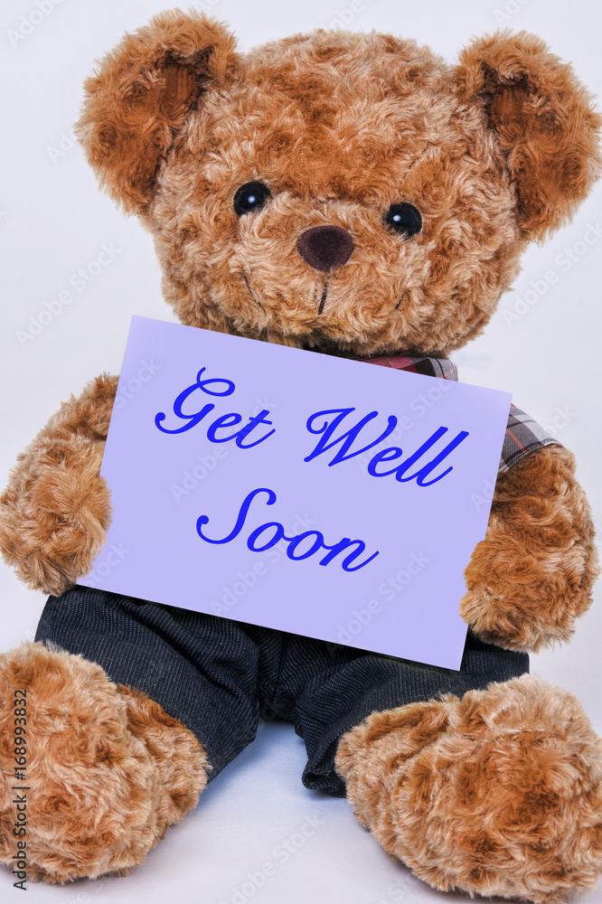 Teddy bear holding a purple sign that says Get Well Soon Stock Photo