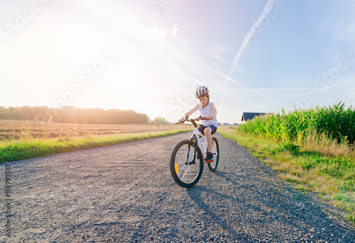 Boy child in white bicycle helmet riding on bicycle