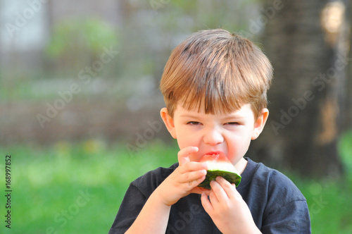 Boy eating watermelon. Four years old boy eats a slice of watermelon