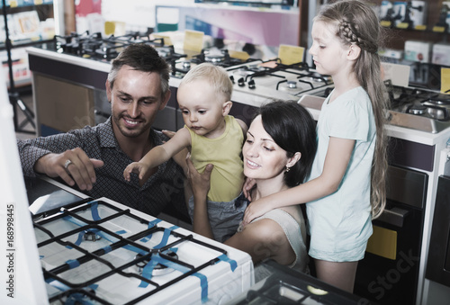 parents with two kids choosing new gas-stove in home appliance store