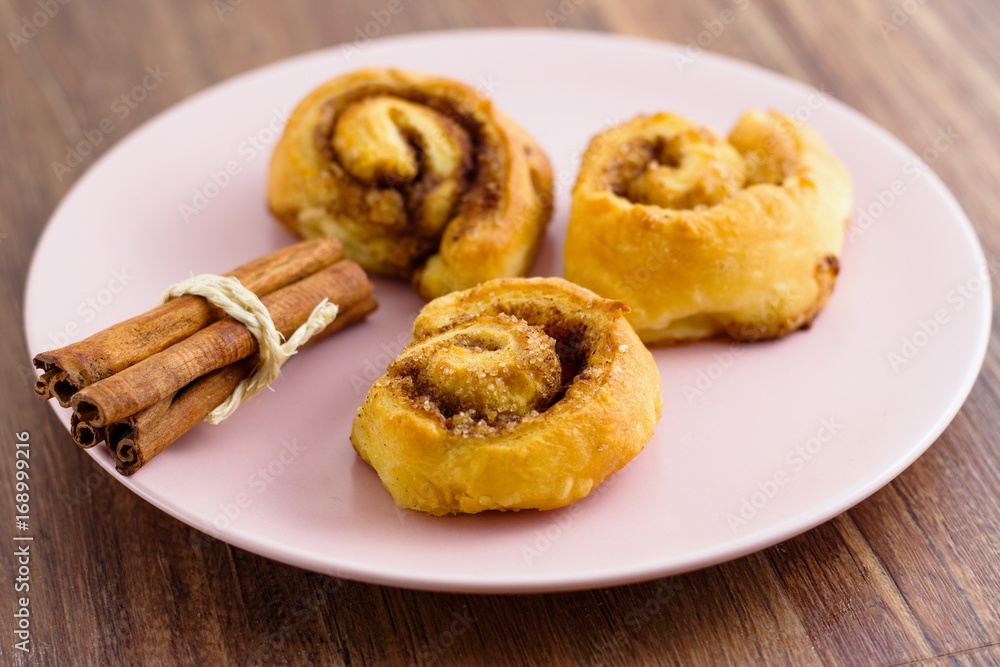 Three cinnamon rolls served and ready to eat on pink plate