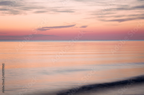 Sea water reflecting a pink heavenly colors and creating a romantic atmosphere in summer evening. Nature background. © fotoduets
