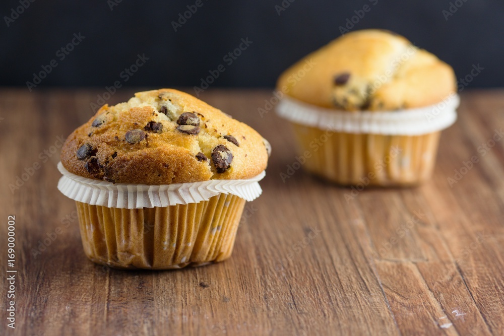 Two chocolate chips vanilla flavor muffins. Selective focus on the front one. Two chocolate chips vanilla flavor muffins. Selective focus on the front one.