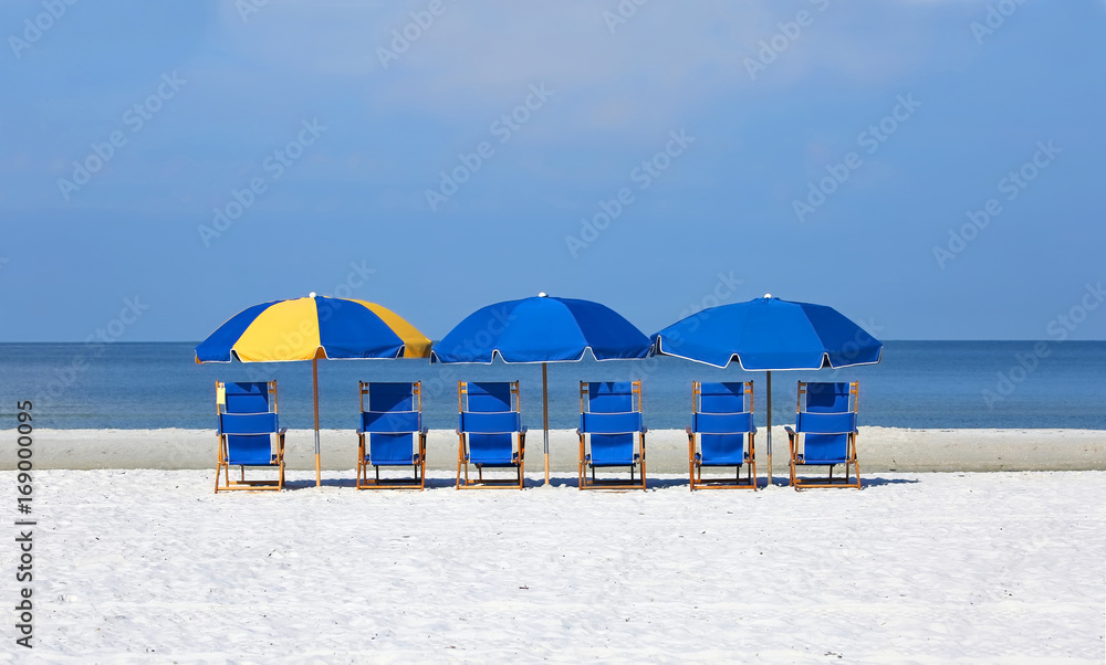 Beach chairs and umbrellas lined up in front of the blue waters of the Gulf of Mexico in Fort Myers Beach, Florida, USA.