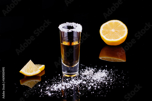 Gold Mexican tequila with salt on black background. Alcoholic drink concept. selective focus