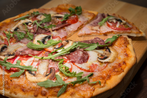 Pizza with champignons and arugula on a wooden plate 