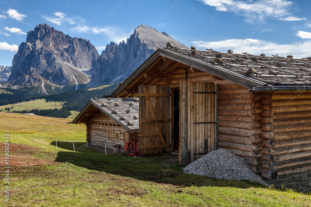Couple of mountain huts in the meadows in the background of the Dolomites Couple of mountain huts in the meadows in the background of the Dolomites