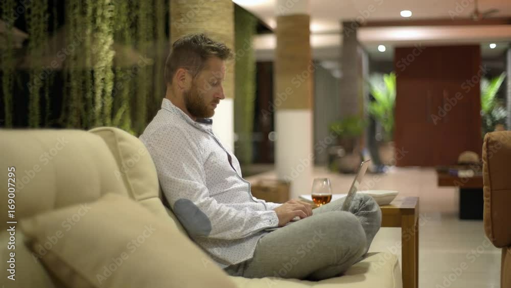 Man sitting on the sofa with his legs crossed and typing on laptop
Man sitting on the sofa with his legs crossed and typing on laptop