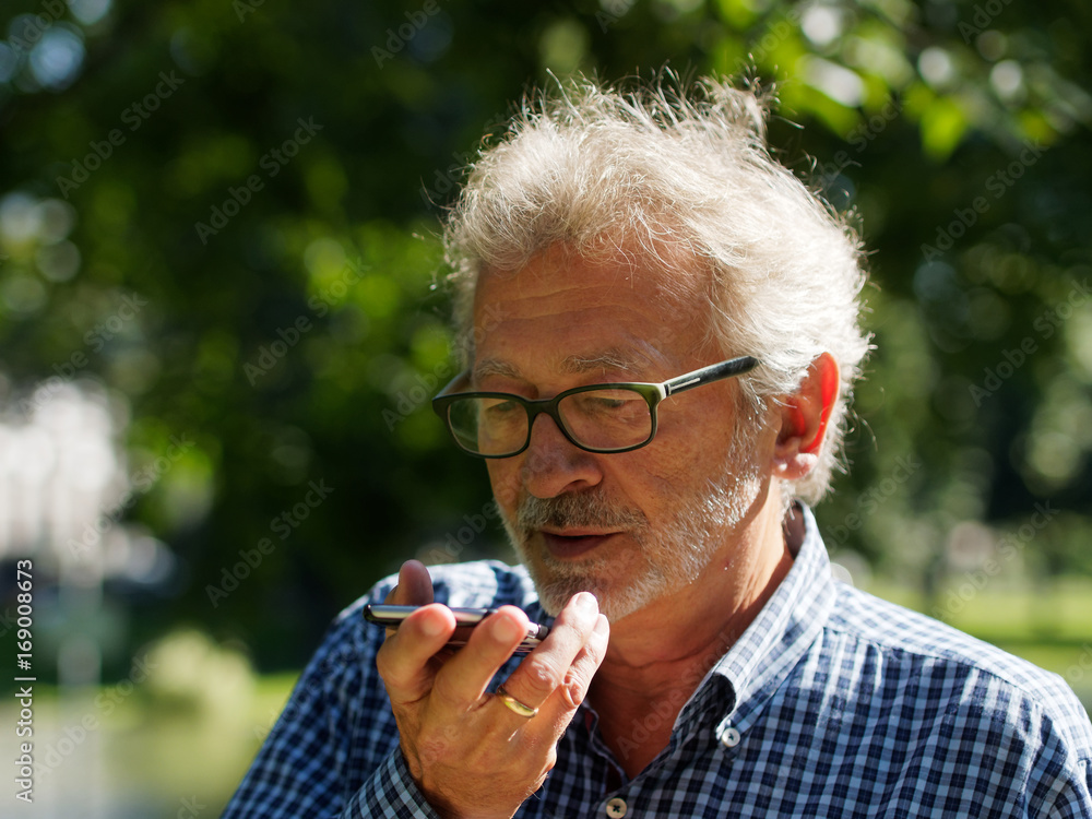 Aktiver Rentner im Park spricht ins Smartphone Aktiver Rentner im Park spricht ins Smartphone