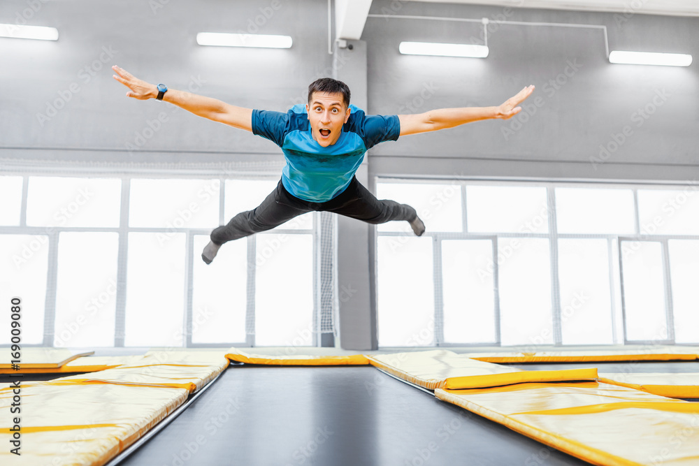 A young fit happy man jumping and flying on trampoline in fitness gym Stock  Photo | Adobe Stock