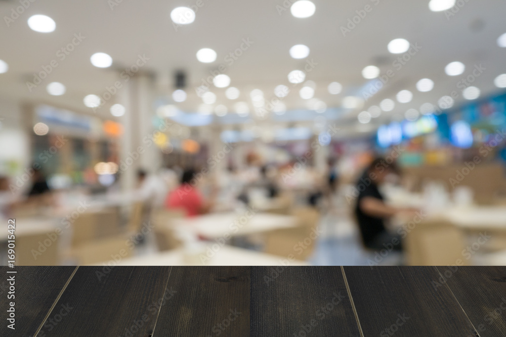 wooden table with abstract blur of food court background