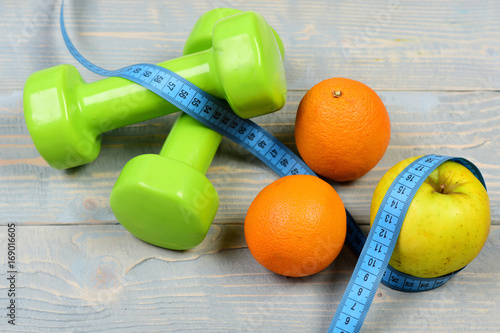 burning calories concept, dumbbells weight with measuring tape, fruit