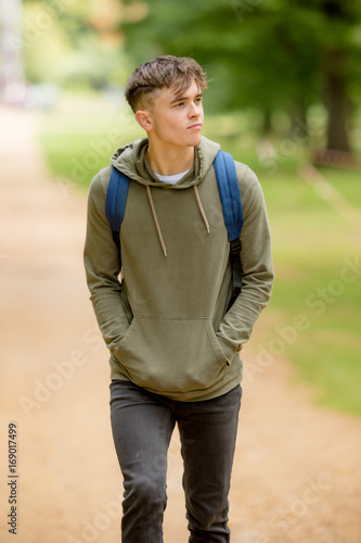Teenage boy walking in a park on a summers afternoon