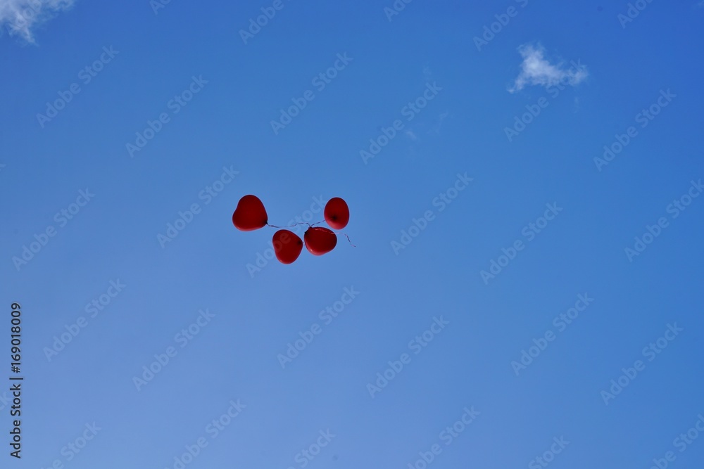Heart shaped red balloons flying loose on a blue sky Heart shaped red balloons flying loose on a blue sky