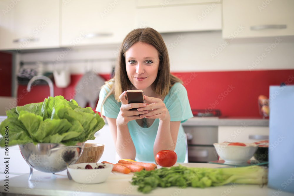 Girl reading a recipe on her smart phone Girl reading a recipe on her smart phone