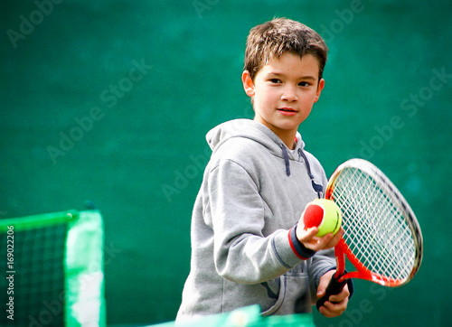 Little tennis player on a blurred green background © Stratos Giannikos