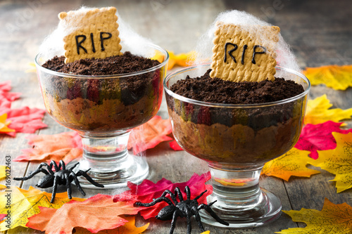 Fotografia Funny Halloween chocolate mousse with tomb cookie on wooden table