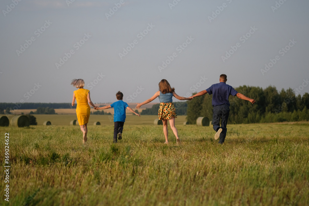 mom, dad, son and daughter running across the field mom, dad, son and daughter running across the field