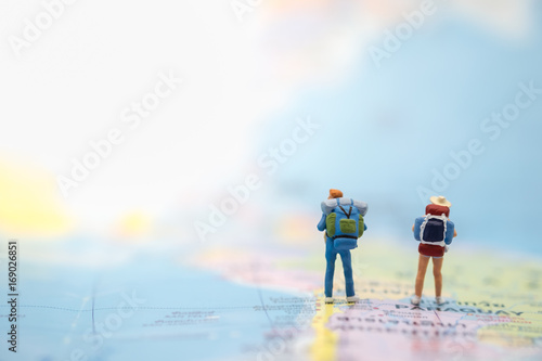Travelling concepts. Two of miniature mini figures with backpack standing on map