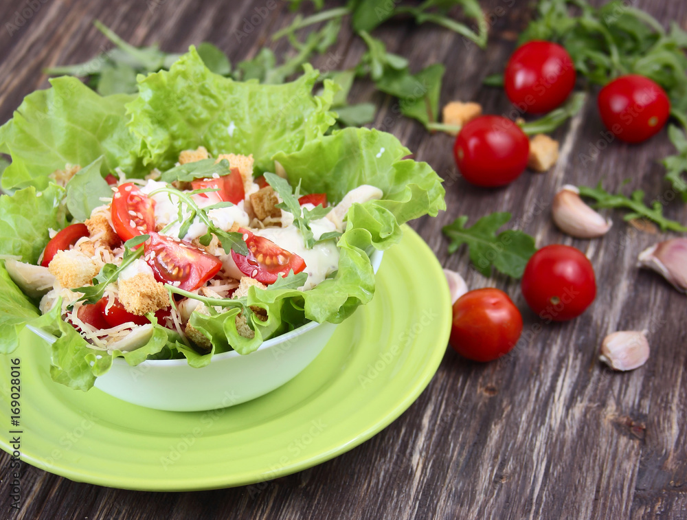 Caesar salad and fresh tomatoes on a wooden table Caesar salad and fresh tomatoes on a wooden table