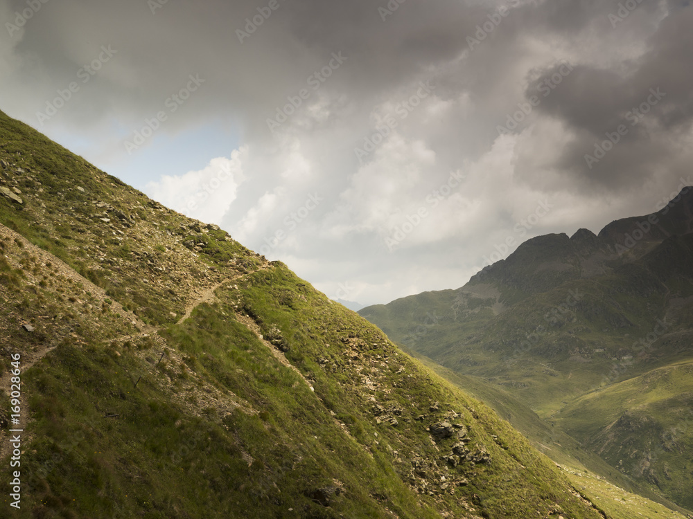Track along a mountain side with view across the valley and the mountains Track along a mountain side with view across the valley and the mountains