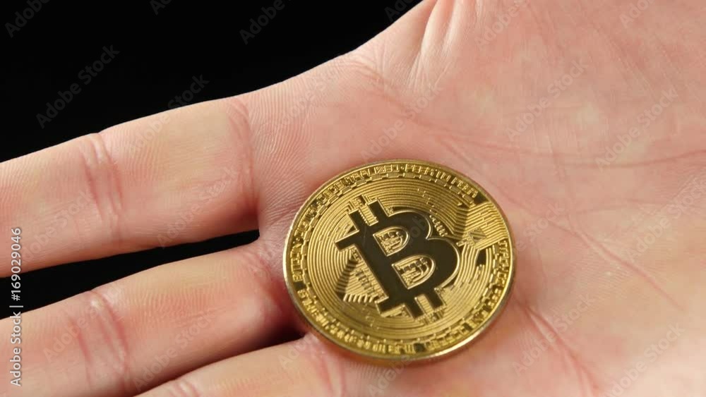 Golden Bitcoin in a man's hand. Symbol of a new virtual currency . Golden Bitcoin in a man's hand. Symbol of a new virtual currency .