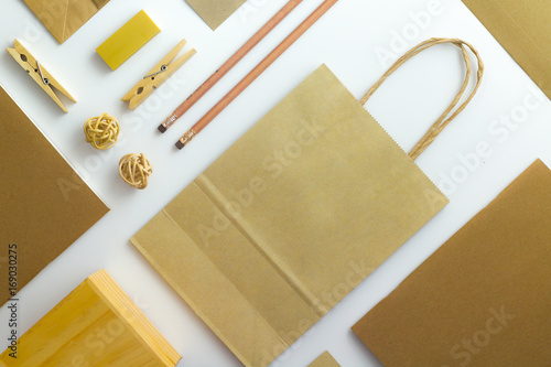 Top view of white table with pencil, notebook, brown paper and paper bag
