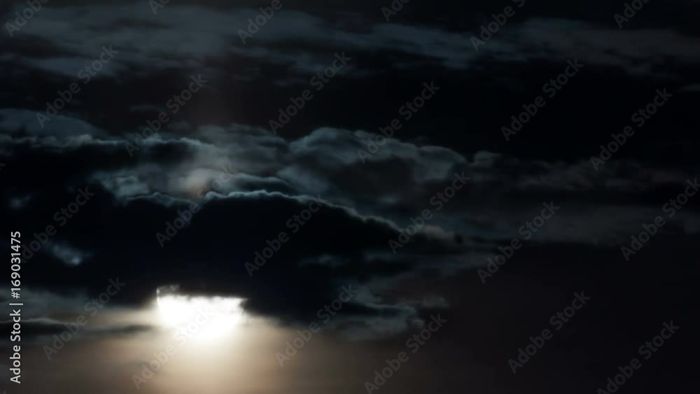 Time-lapse. Full moon close-up rises through the clouds in the dark. Time-lapse. Full moon close-up rises through the clouds in the dark.