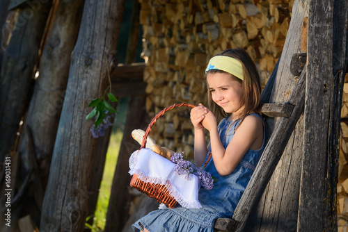 Cute smiling little girl holding a basket of flowers. Portrait in profile. photo