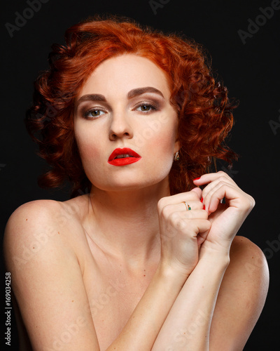 Fotografie A beautiful girl with red hair looks anxiously at the camera.