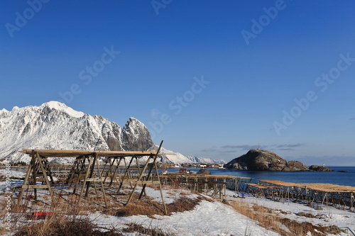 Empty hjells-wooden racks-fish dryers-Reine village. Lilandstinden-Festhaeltinden mounts background. Lofoten-Nordland-Norway. 0303 photo