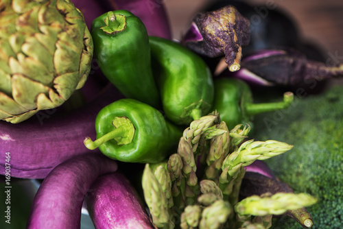 Nice raw vegetable still life of thin purple eggplants, green paprika peppers, plumps, artichoke, brocoli and asparagus. Fresh food life style.