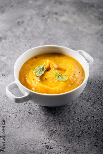 Creamy pumpkin soup puree in tbowl on table ready to eat