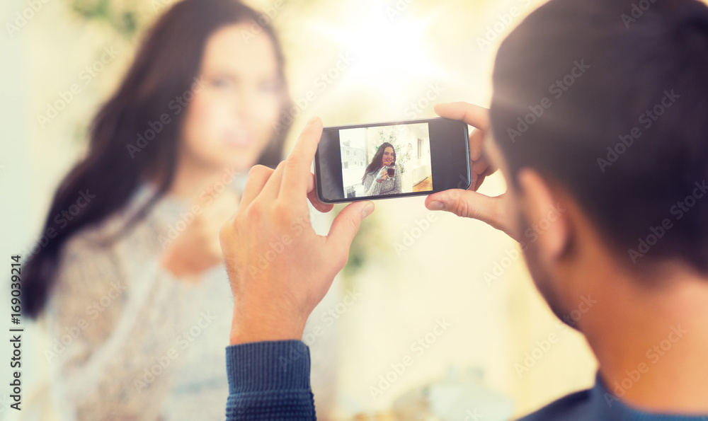 man taking picture of woman by smartphone at cafe man taking picture of woman by smartphone at cafe