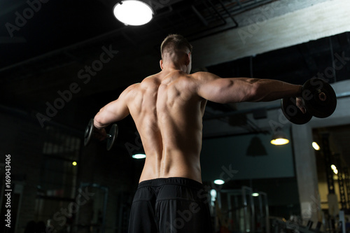 close up of man with dumbbells exercising in gym