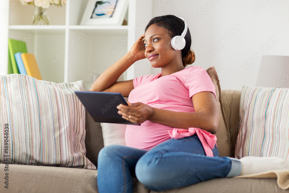 pregnant woman in headphones with tablet pc pregnant woman in headphones with tablet pc