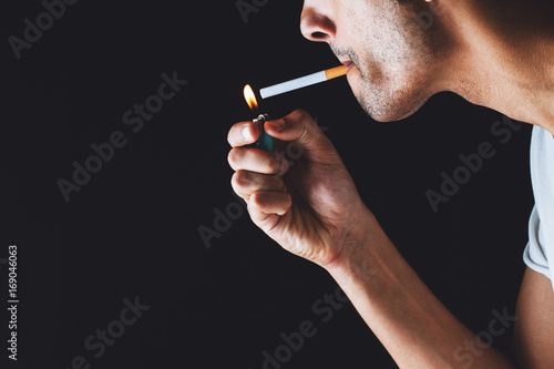 close-up of a man lighting a cigarette in a dark atmosphere