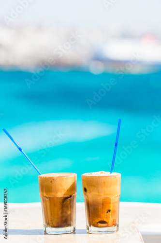 Frappe, ice coffee on the beach. Summer iced coffee frappuccino, frappe or latte in a tall glass background the sea in beach bar